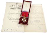 un vieux document orné d'un ruban rouge et d'une médaille, présenté dans un écrin