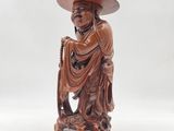 an old wooden statue of a man wearing a hat and holding a cane