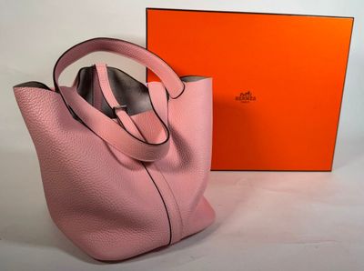 un sac à main rose et une boîte orange posés sur une surface blanche