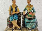 pair of ceramic figurines of a woman and a man sitting on a bench