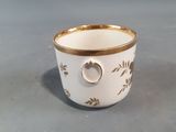 a white cup with a gold rim on a gray surface