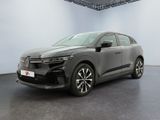 La voiture grise est garée dans une grande pièce au sol noir.