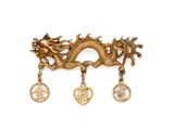an image of a gold dragon broochle with three charms on it