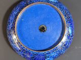 an image of a blue and gold plate on a gray surface
