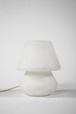 une lampe blanche posée sur une table près d'un mur blanc