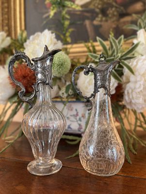 deux vases posés sur une table, avec des fleurs en arrière-plan