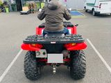a man riding a red four wheeler atv in a parking lot