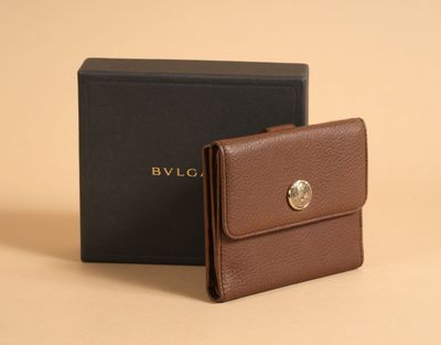 the brown wallet is next to a black box on a beige surface