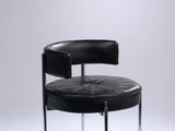un fauteuil en cuir noir avec des pieds chromés et une assise ronde