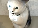 une figurine de chat posée sur une table, avec une étiquette autour du cou