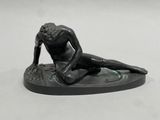 a statue of a man sitting on a surfboard on a white surface