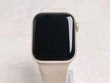 a white apple watch with a black face sitting on a clear stand