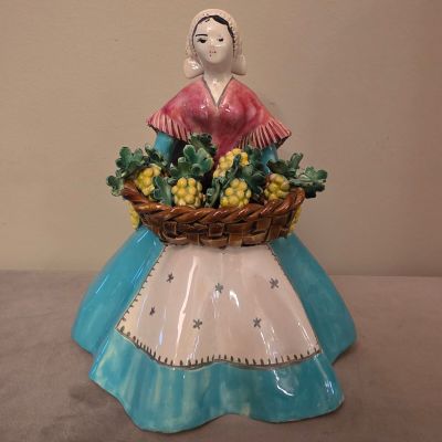 une figurine représentant une femme tenant un panier de raisins