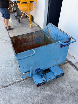 une brouette bleue sur le trottoir, à côté d'une machine jaune