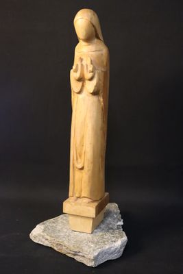 a wooden statue of a woman holding a child on a rock