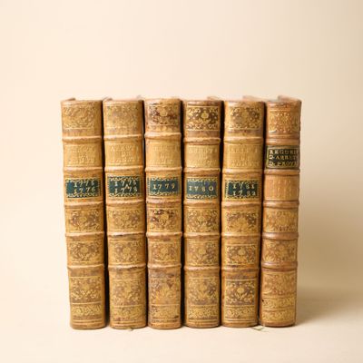 six vieux livres alignés sur une surface blanche