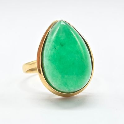 une image représentant une bague en pierre verte posée sur une surface blanche