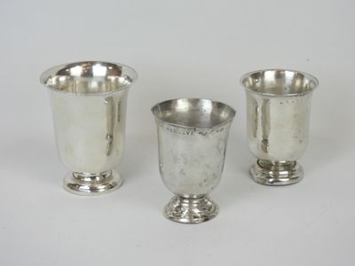trois tasses en argent posées l'une à côté de l'autre sur une surface blanche
