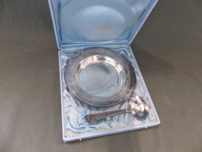 un plateau en argent avec une cuillère et un repose-cuillère, dans une boîte bleue