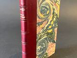 a red book sitting on top of a table next to a gray wall