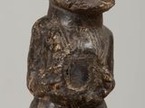 une vieille statue en bois représentant un homme tenant un bébé dans ses bras, posée sur une table en bois