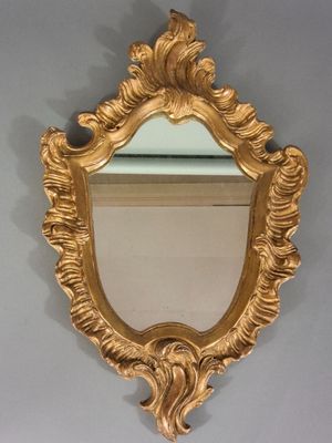 un miroir doré accroché au mur au-dessus d'un lavabo