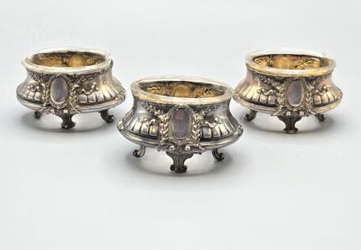 trois vases en argent empilés les uns sur les autres sur une surface blanche