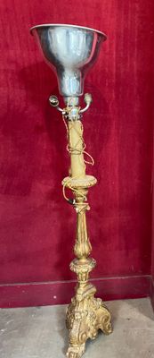 a silver vase that is on a stand in front of a red wall