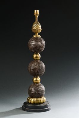 une image représentant une lampe dorée et noire surmontée de trois boules