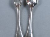 two silver spoons and a fork on a table