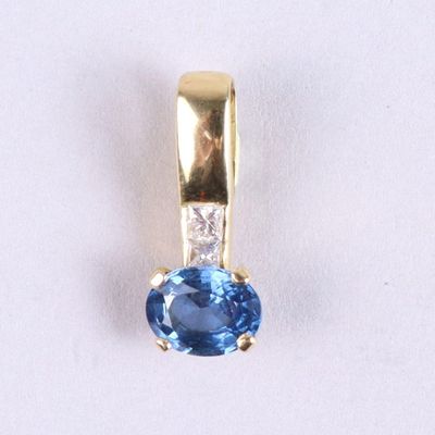 un gros plan d'un pendentif en saphir bleu et diamants sur une surface blanche