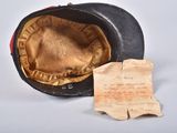 a black hat with a red band and a piece of paper