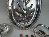 a silver plate with a tree on it next to other silver dishes