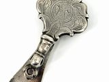 une cuillère en argent avec un manche en argent posée sur une surface blanche