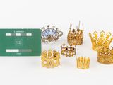 a group of gold crowns and a green card on a white surface