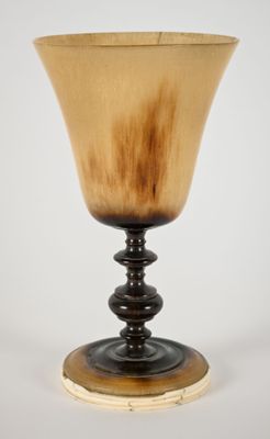 un verre avec un pied en bois sur fond blanc