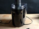 un mixeur noir posé sur une table en bois, à côté d'un téléphone portable