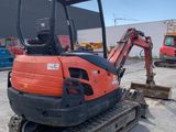 an orange and black mini excavator parked in a parking lot
