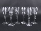 six clear wine glasses lined up against a black background
