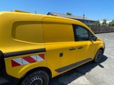 the yellow van is parked in the parking lot near a fence