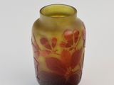 a yellow vase with red flowers on it on a white surface