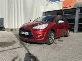 La petite voiture rouge est garée devant un immeuble.