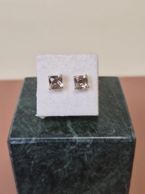 a close up of a pair of earrings sitting on top of a marble block
