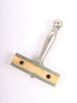 a wooden stamp with a metal handle on a white surface
