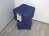 un petit tabouret bleu posé contre un mur blanc