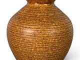 un vase brun posé sur une surface blanche