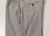 un gros plan sur un pantalon gris posé sur une surface blanche