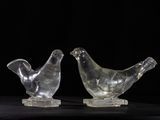 two clear glass birds sitting on top of each other on a black surface