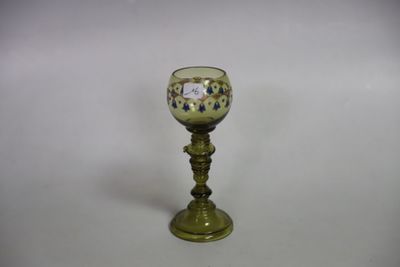 un petit verre vert avec un pied doré sur fond blanc