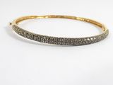 un bracelet rigide en or et diamants sur fond blanc